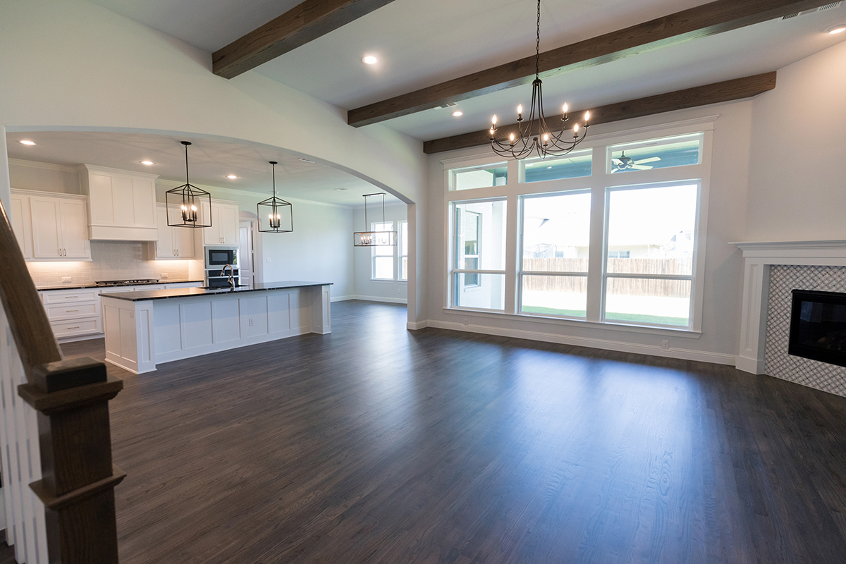 Spacious open floor plan with a modern kitchen, dining area, and living room featuring large windows and natural light.