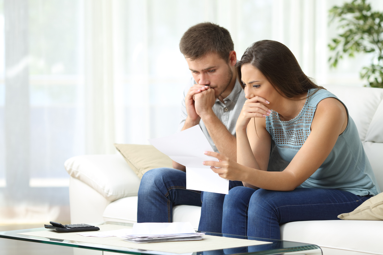 A couple reviewing financial documents to avoid foreclosure in today’s market.